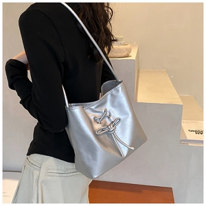 Silver metallic shoulder bag with knot detail shown on model for size perspective