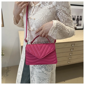 Close-up of rose pink quilted leather handbag with gold hardware and V-pattern stitching