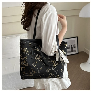 Close-up of black tote bag with gold butterfly embroidery and white silk ribbon detail