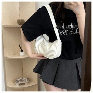 Detail of white pleated underarm bag with oval logo plaque and matte PU leather texture