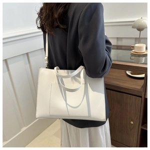 White leather tote bag with large front pocket styled on a model for urban commute look