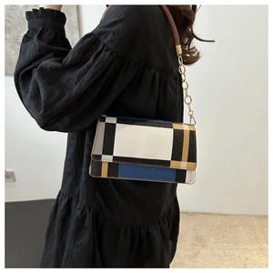 Detail of color-block flap shoulder bag with gold chain strap on a model outfit