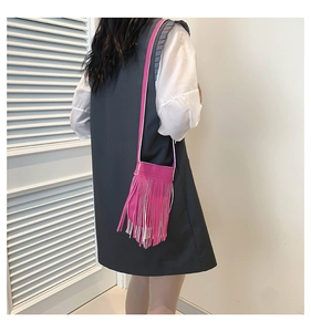 Detail of fuchsia leather crossbody bag featuring long tassels and slim shoulder strap