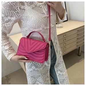 Detail of rose pink quilted leather handbag featuring a V-shaped pattern and short handle