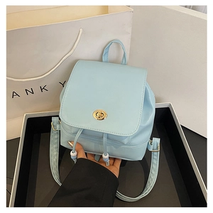 Detail of light blue mini backpack featuring gold turn-lock and pearl drawstring accents