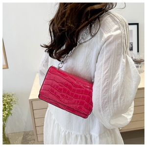 Close-up of bright pink crocodile pattern crossbody bag with silver chain strap