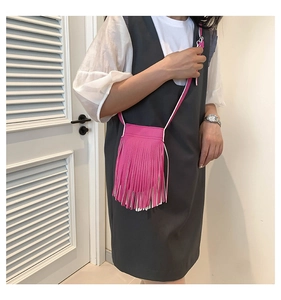 Close-up of bright pink fringe crossbody bag featuring textured leather and long tassels