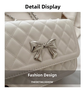 Close-up of white quilted chain bag featuring a silver metal bow buckle detail