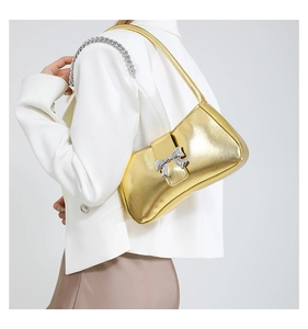 Detail der goldenen Metallic-Umhängetasche mit Silberschleife und Y2K-Kettendesign