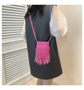 Back view of a person wearing a fuchsia tassel crossbody bag over a grey vest dress