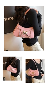 Detalle de bolso rosa con adorno de mariposa plateada y correa de cadena metálica