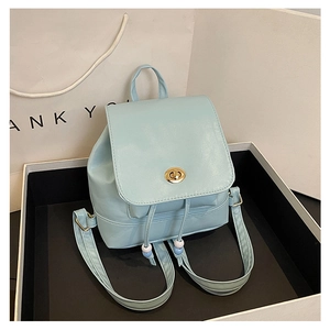 Detail of light blue mini backpack with golden turn-lock and drawstring closure mechanism