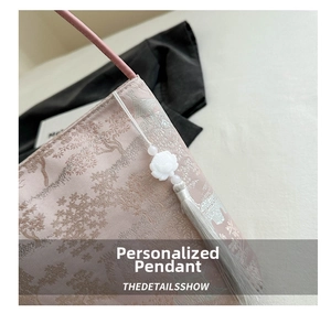 Detail der rosa Jacquard-Beuteltasche mit floralem Anhänger und eleganter Quaste