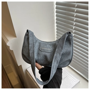 Detailed close-up of a grey crescent shoulder bag with a textured matte finish and logo