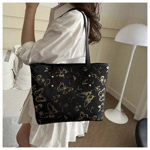 Detail of a black butterfly print tote bag with gold rivets and slim shoulder straps