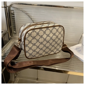 Détail du motif trèfle sur sac bandoulière beige avec finitions en cuir brun