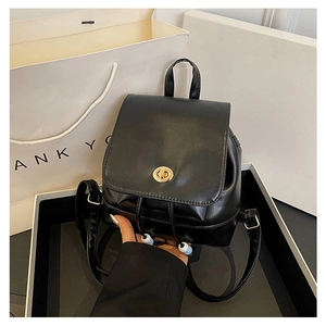 Detailed macro view of black mini backpack with gold metal twist lock and smooth leather texture