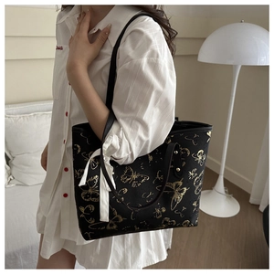 Detail of black jacquard tote bag with gold butterfly pattern and white ribbon bow