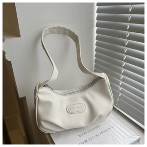 Close-up of beige textured PU leather baguette bag with zip closure and fashion logo tag