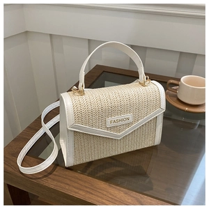 Détail d'un sac à main en paille tressée avec garniture en cuir blanc et boucle en métal