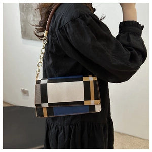 Detail of color-block geometric shoulder bag with gold chain strap on a model