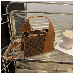 Nahaufnahme der Vintage-Box-Tasche mit Monogramm-Muster und Ledergriff auf Metallregal