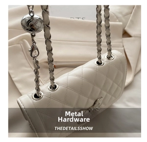 Detail of white quilted leather bag showing the metal chain and bow clasp design