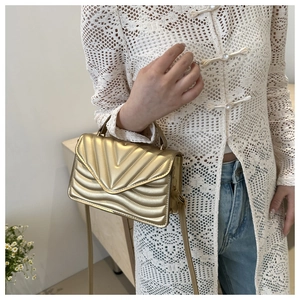 Close-up of golden quilted crossbody bag featuring a unique V-pattern and chain strap