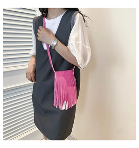 Detail view of stylish pink crossbody bag with dual-tone tassels on a female model