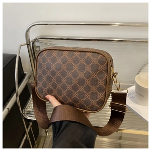 Détail d'un sac bandoulière marron rétro avec motif trèfle et large bandoulière en tissu