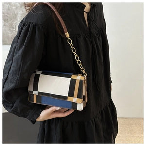 Detail of fashion crossbody bag with geometric patchwork and gold chain strap