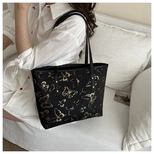 Close-up of black tote bag with detailed gold butterfly embroidery and dual shoulder straps