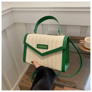 Détail macro du sac en paille avec garniture en cuir PU vert et finitions dorées