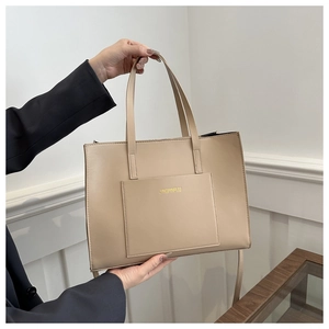 Detailed close-up of beige tote bag with golden brand lettering and fine PU leather texture