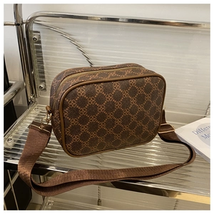 Détail d'un sac bandoulière marron avec motif trèfle et large bandoulière tissée