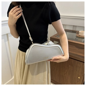 Detail of silver metallic crescent shoulder bag with glossy finish and brand lettering