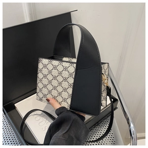 Detailansicht der Handtasche mit schwarz-weißem Kleegittermuster und Goldbeschlägen