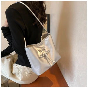 Detail shot of a silver metallic tote bag with decorative cross-lacing and bow design