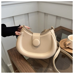 Detail of a minimalist cream PU leather crescent shoulder bag with a magnetic buckle