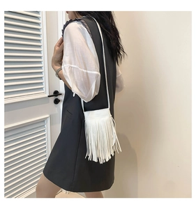 Close-up of a white fringe crossbody bag shown on a model for a stylish casual look