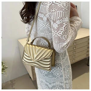 Detail of golden V-quilted crossbody bag with top handle and fine shoulder strap