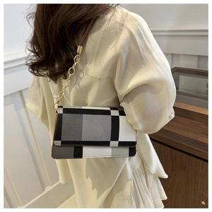 Detail of retro black and white plaid shoulder bag with gold chain and leather handle