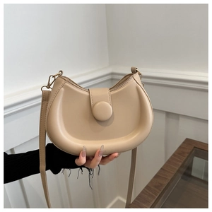 Detail of the minimalist beige crescent crossbody bag with smooth leather finish and strap