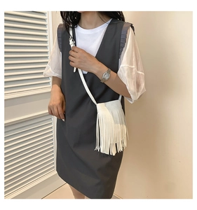 Detailed view of white fringed crossbody bag paired with minimalist summer outfit