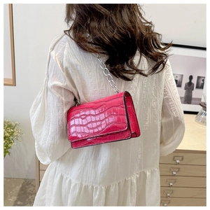 Close-up of rose red crocodile pattern leather crossbody bag with silver chain strap