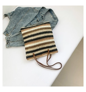 Detailed top view of large striped straw tote bag with brown handles and zipper