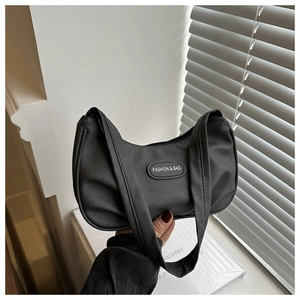 Detail showing crescent-shaped black nylon shoulder bag with fashion leather tag logo