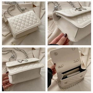 Detail view of white quilted crossbody bag with bow clasp and silver chain strap
