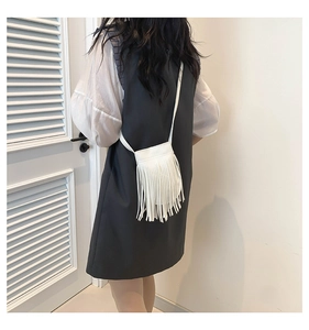Detail of white mini crossbody bag featuring dense fringe tassels and slim shoulder strap