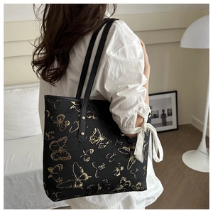 Close-up of golden butterfly embroidery and metal rivet details on the black tote bag